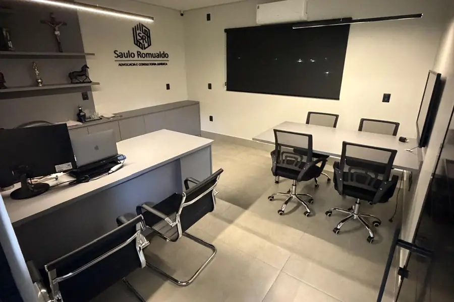 Interior do escritório em Formosa: mesa de atendimento, logomarca na parede e mesa de reuniões
